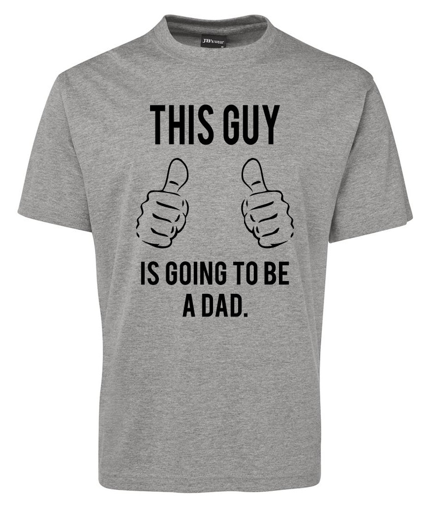 The Corsa Clothing Going to be DAD Shirt is a gray tee with black "THIS GUY IS GOING TO BE A DAD" text and two illustrated hands with thumbs up below "THIS GUY," above the rest of the message.