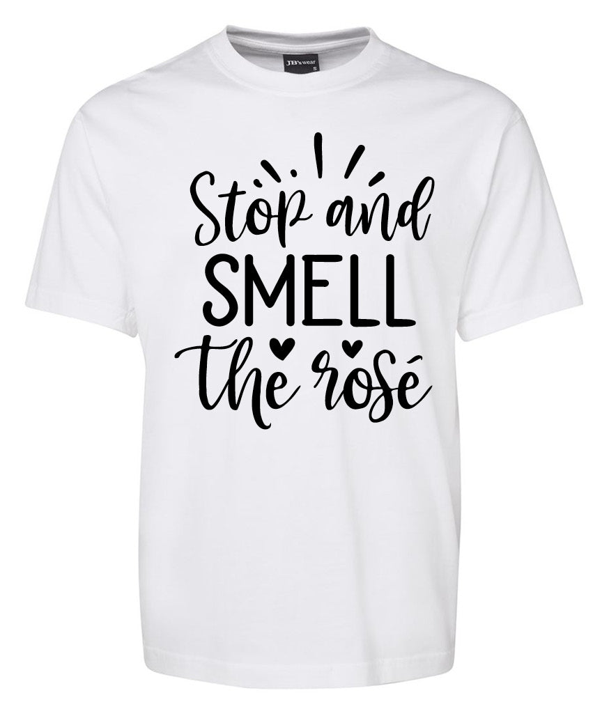The Stop and smell the rose Shirt by Corsa Clothing is a white tee featuring "Stop and SMELL the rose" in black script, accented with small hearts and lines.