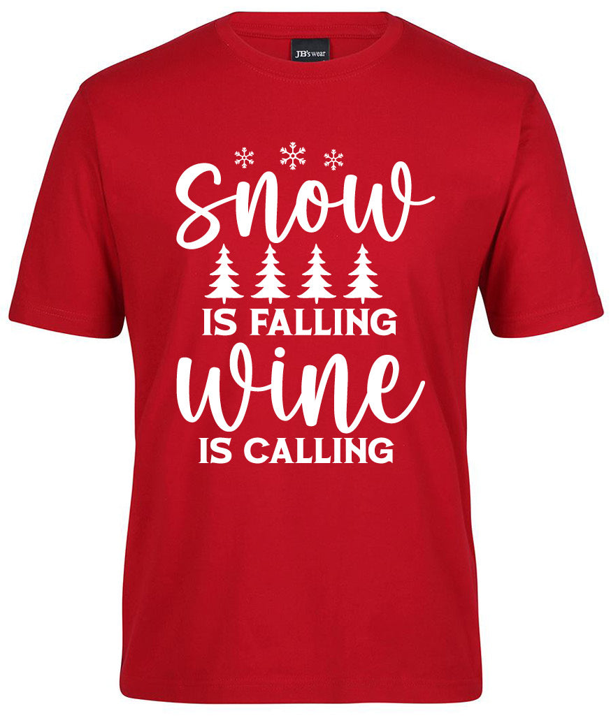 The Snow is falling Wine is Calling Shirt by Corsa Clothing features white text and snowflake graphics with tree icons on a red tee.