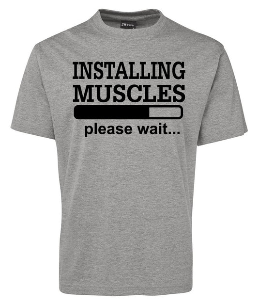 The Corsa Clothing INSTALLING MUSCLES Shirt is a gray tee featuring black text that says "INSTALLING MUSCLES" above a loading bar graphic, with "please wait..." below the bar.