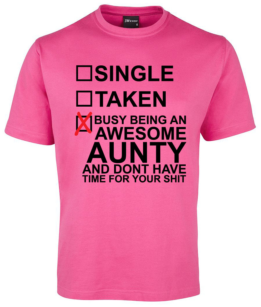 The Relation Status Checkbox Shirt by Corsa Clothing is a pink tee featuring Single, Taken, and Busy being an awesome aunty—red X checked on the last option.