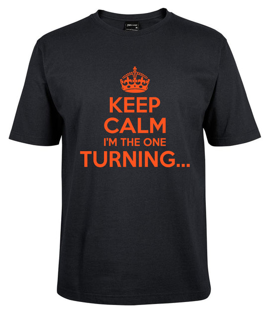The Corsa Clothing KEEP CALM I'M THE ONE TURNING Shirt features a black design with an orange crown and bold orange text printed on the front.