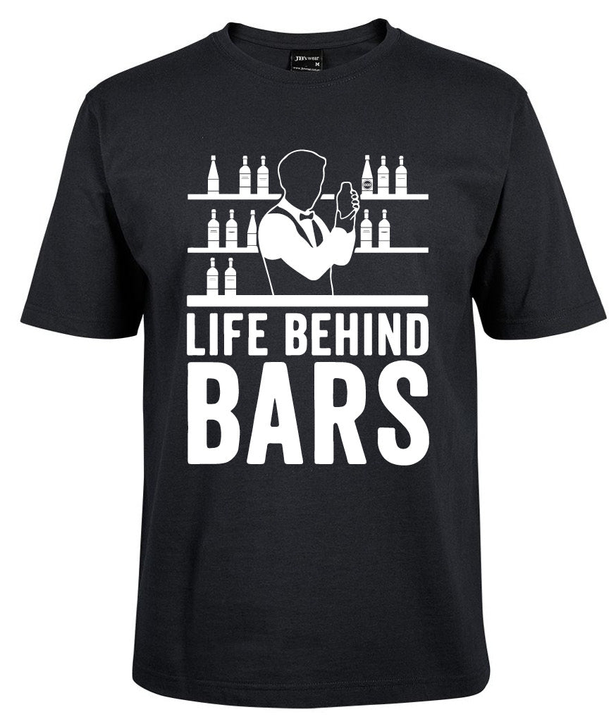 The Life Behind Bars Shirt by Corsa Clothing is a black tee with a bartender mixing drinks before shelves of bottles, and "LIFE BEHIND BARS" boldly printed in white.