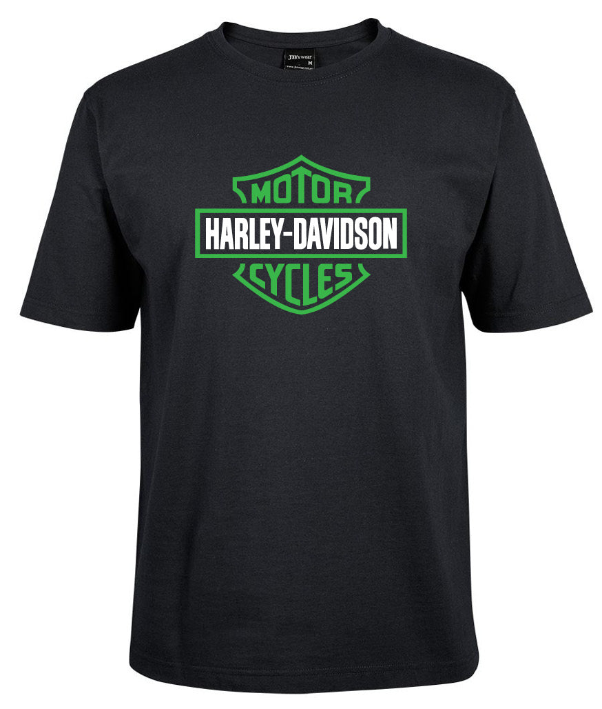 The Corsa Clothing Harley-Davidson Bar & Shield Shirt Green is a black tee with a bold green and white Harley-Davidson Motor Cycles logo and HARLEY-DAVIDSON in white text inside a green-outlined shield on the front.