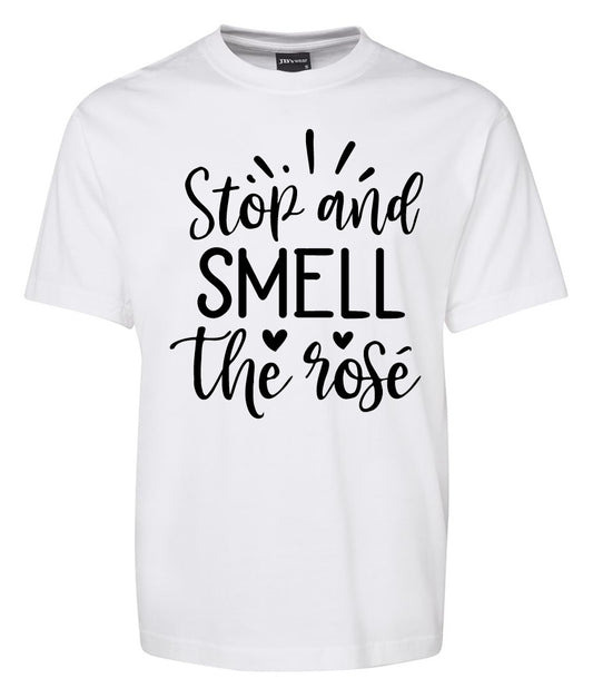 The Stop and smell the rose Shirt by Corsa Clothing is a white tee featuring "Stop and SMELL the rose" in black script, accented with small hearts and lines.
