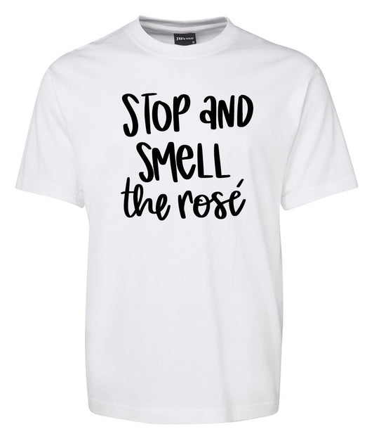 The "Stop and smell the rose" white t-shirt by Corsa Clothing features bold, black, playful lettering on the front.