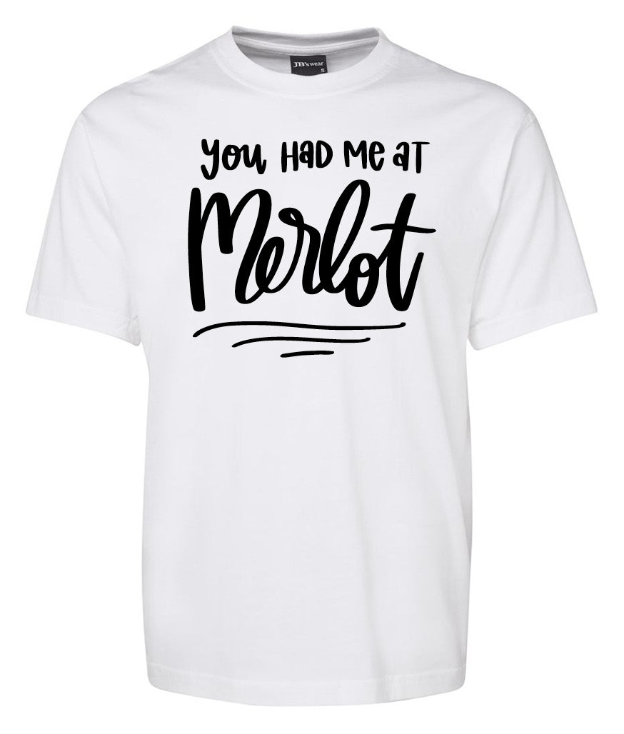 The Corsa Clothing You had me at Merlot Shirt is a white T-shirt featuring the phrase "You had me at Merlot" in bold, playful black cursive and script fonts on the front.