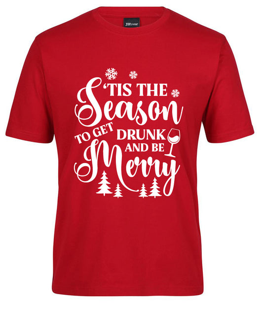 The Season 'TIS THE DRUNK TO GET Merry Shirt by Corsa Clothing is a red tee featuring white festive text, snowflakes, Christmas trees, and a wine glass.