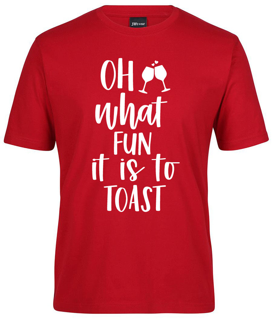 The Oh what fun it is to Toast Shirt by Corsa Clothing features playful white text and two clinking wine glasses above "what" on a red t-shirt.